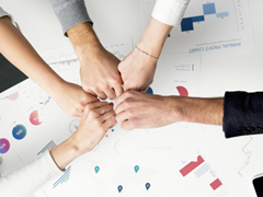 5 workers putting fists together as a team bonding