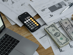 a computer with stacks of money overlaying data files