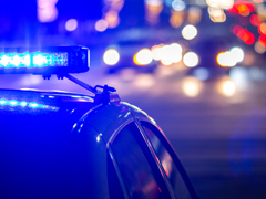 police car with blue light on by a traffic intersection